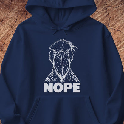 Navy hoodie with a white line-art Shoebill staring straight ahead above the word NOPE, laid flat on a rustic wood background.