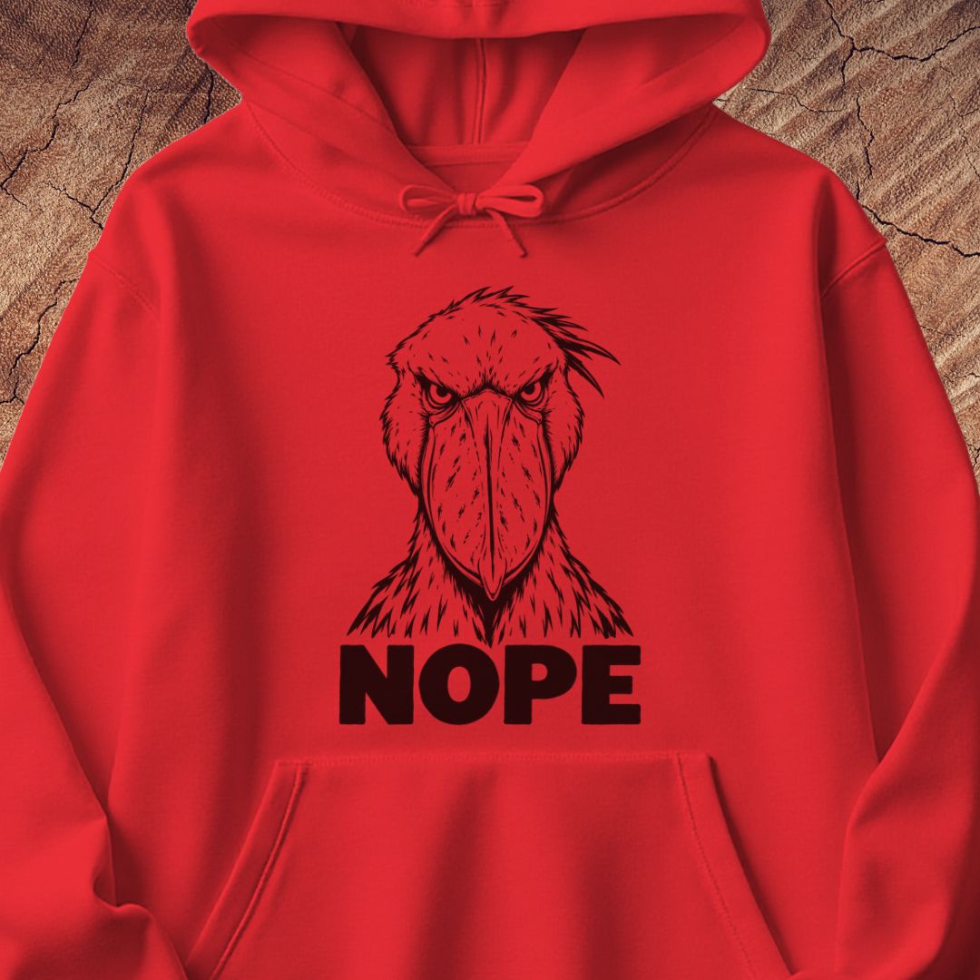 Red hoodie with a black line-art Shoebill staring straight ahead above the word NOPE, laid flat on a rustic wood background.