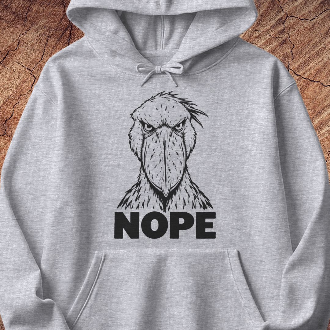 Sport grey hoodie with a black line-art Shoebill staring straight ahead above the word NOPE, laid flat on a rustic wood background.