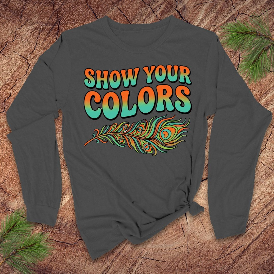 Gray long-sleeve shirt with 'Show Your Colors' text and peacock feather design on a wooden surface.