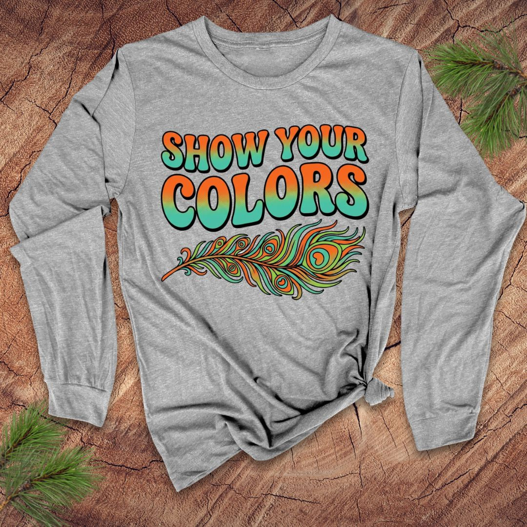 Gray long-sleeve shirt with 'Show Your Colors' text and peacock feather design on a wooden surface.