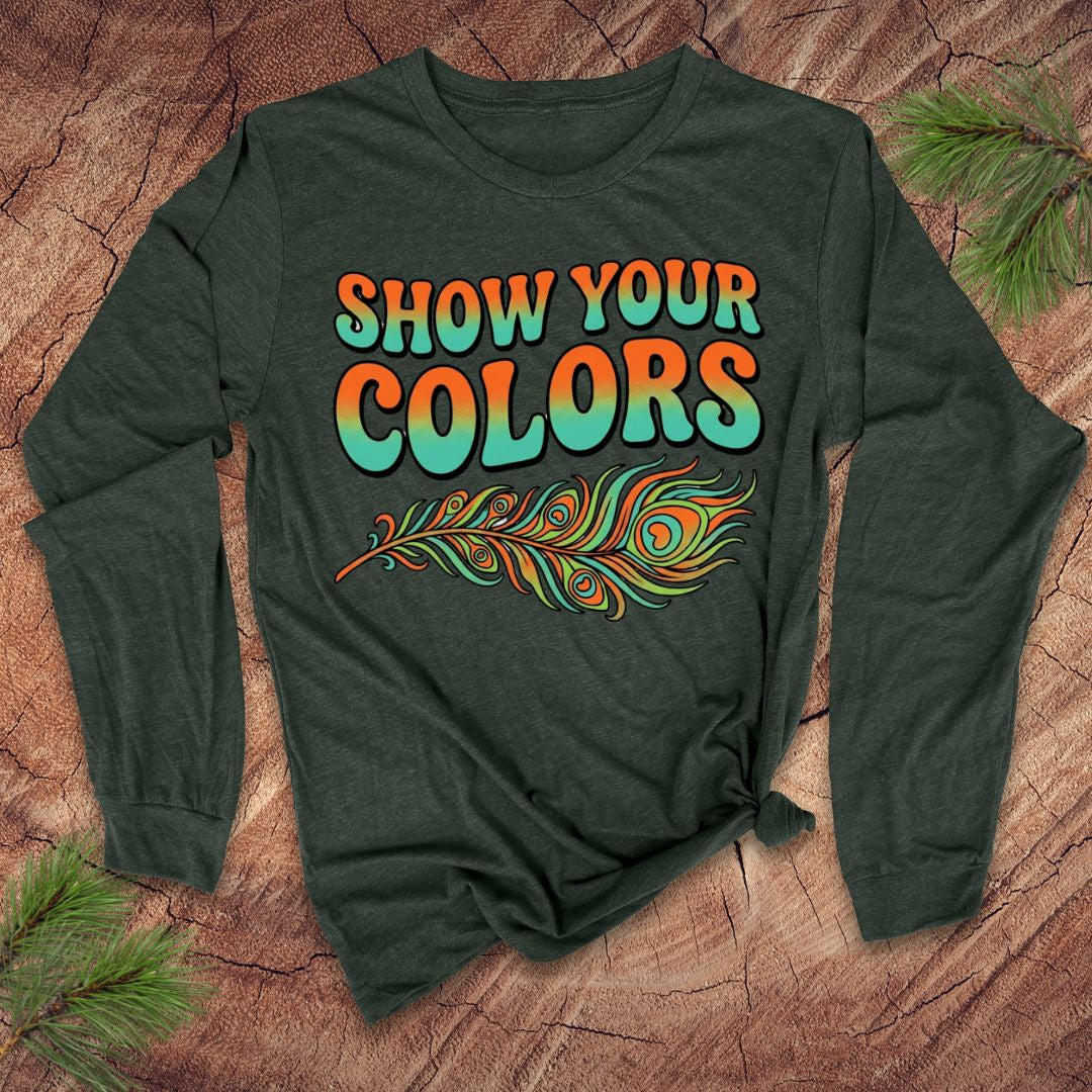 Green long-sleeve shirt with 'Show Your Colors' text and peacock feather design on a wooden surface.