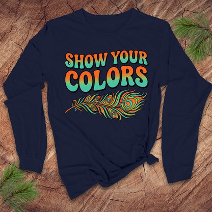 Navy blue long-sleeve shirt with 'Show Your Colors' text and peacock feather design on a wooden surface.