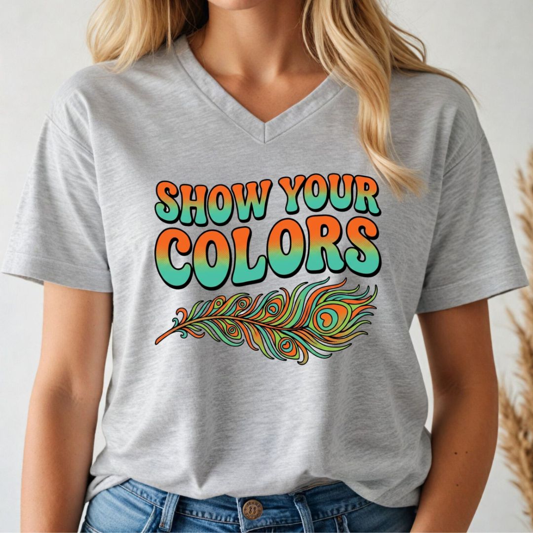 Person wearing a gray v-neck t-shirt with 'Show Your Colors' and a peacock feather design.