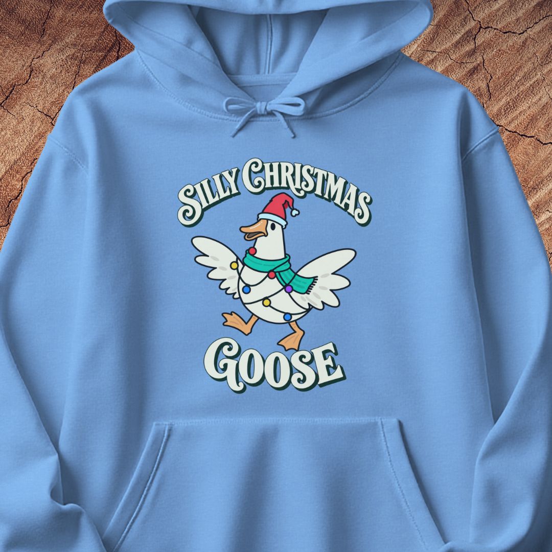Carolina blue hoodie with a goose in a Santa hat and teal scarf, wrapped in colorful Christmas lights under retro Silly Christmas Goose lettering, laid flat on a rustic wood background.