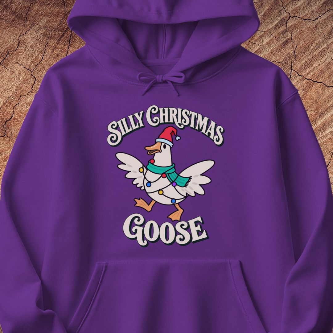 Purple hoodie with a goose in a Santa hat and teal scarf, wrapped in colorful Christmas lights under retro Silly Christmas Goose lettering, laid flat on a rustic wood background.