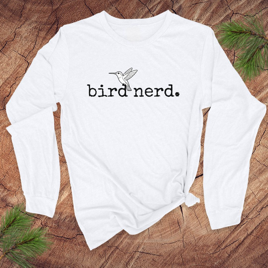 White long-sleeve shirt with 'bird nerd' text and bird graphic on a wooden surface.
