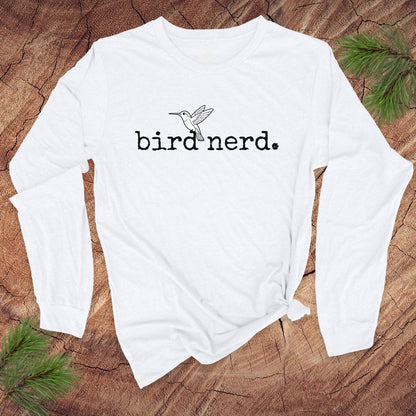White long-sleeve shirt with 'bird nerd' text and bird graphic on a wooden surface.