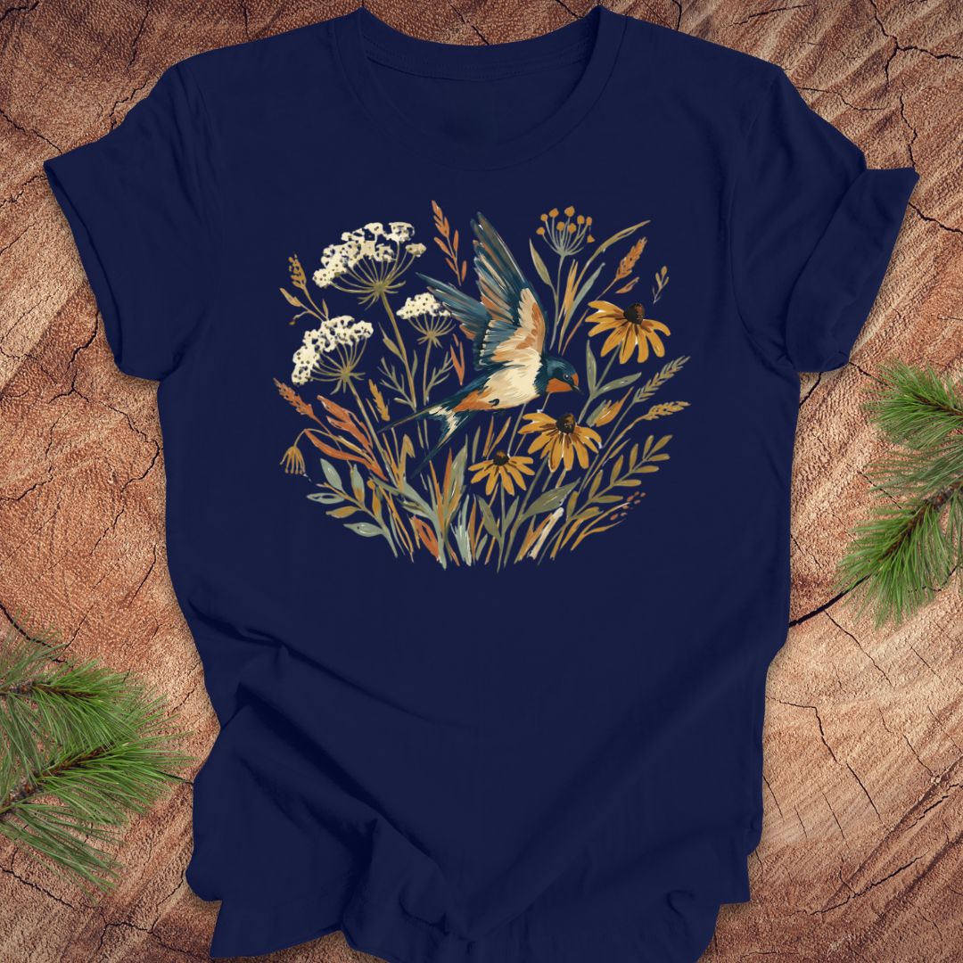Navy blue t-shirt with watercolor flowers and a barn swallow in flight, on a wood background. 