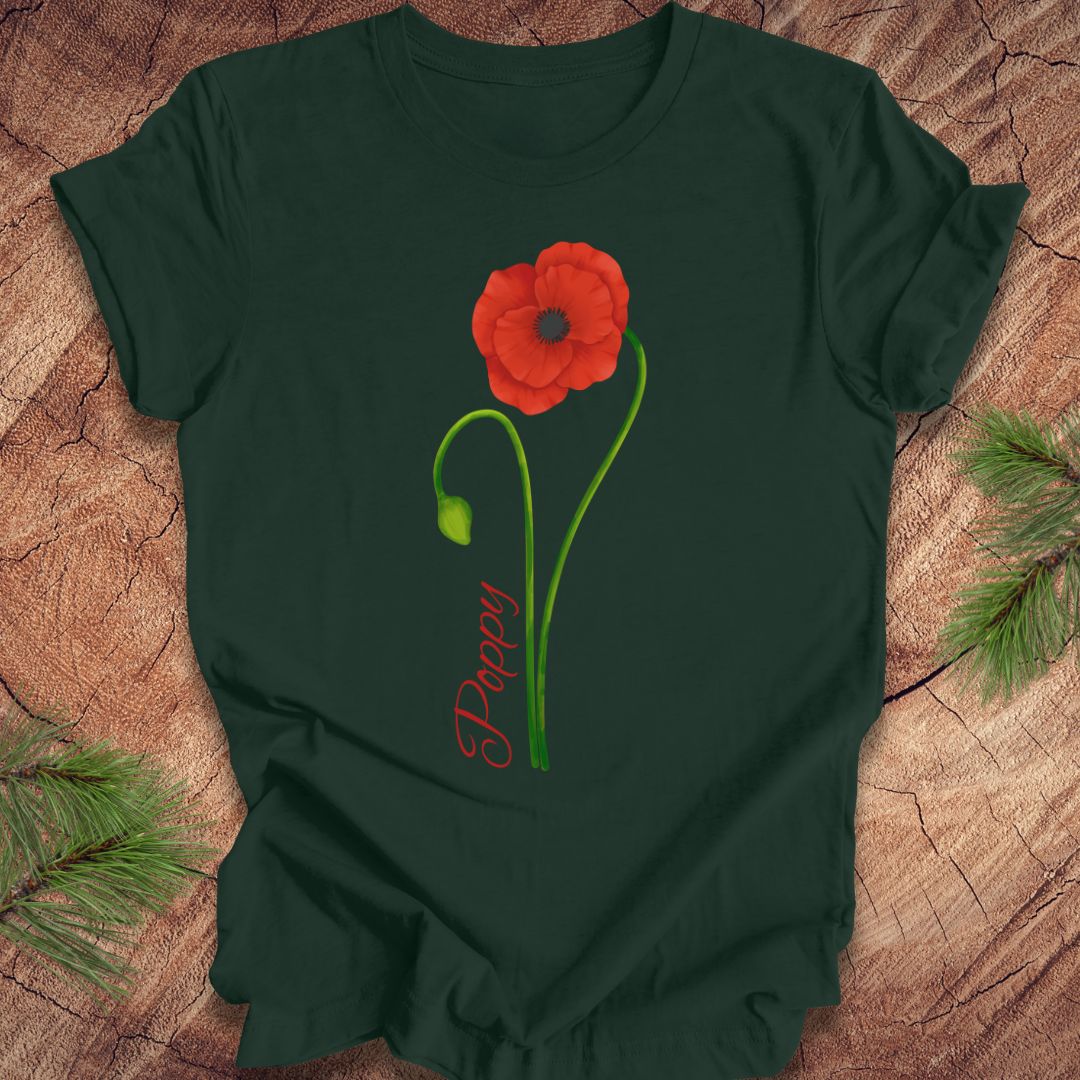 Green t-shirt with a red poppy flower design on a wooden surface