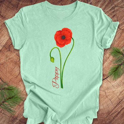 Mint green t-shirt with a red poppy flower and 'Pappy' text on a wooden surface.