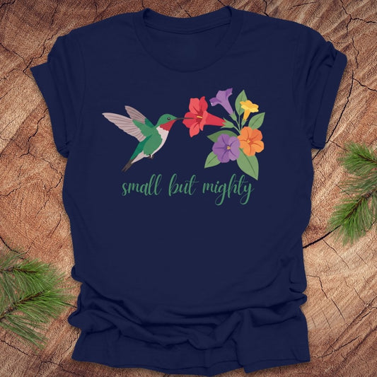 Navy blue t-shirt with a hummingbird and flowers with text, 'small but mighty' on a wooden surface