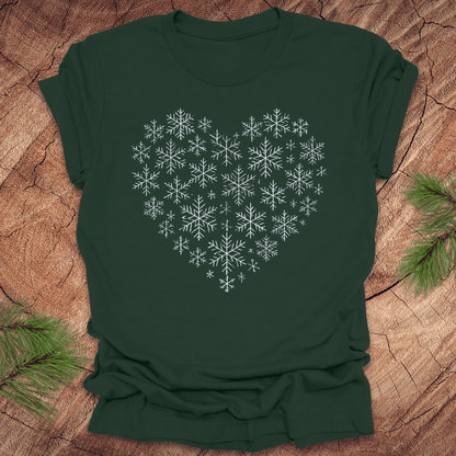Green t-shirt with snowflakes making the shape of a heart on a wood background.