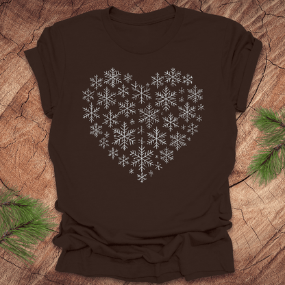 Brown t-shirt with snowflakes making the shape of a heart on a wood background.