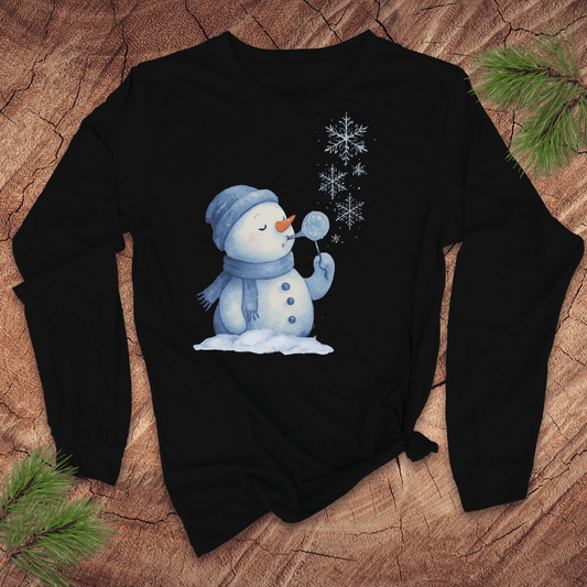 Black long-sleeve shirt with a snowman design on a wooden surface with pine branches.