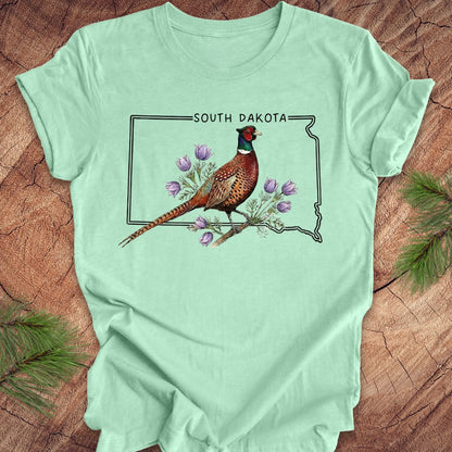 Mint green t-shirt with a pheasant and South Dakota outline design on a wooden surface.
