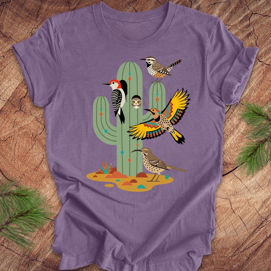 Purple t-shirt with a cactus and birds design on a wooden surface
