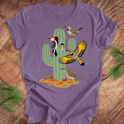 Purple t-shirt with a cactus and birds design on a wooden surface