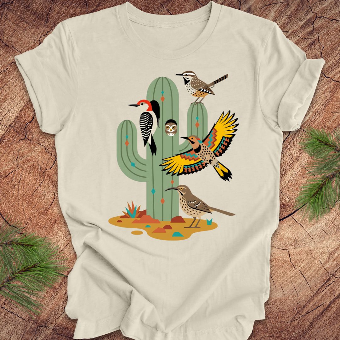 Beige t-shirt with a cactus and birds design on a wooden surface