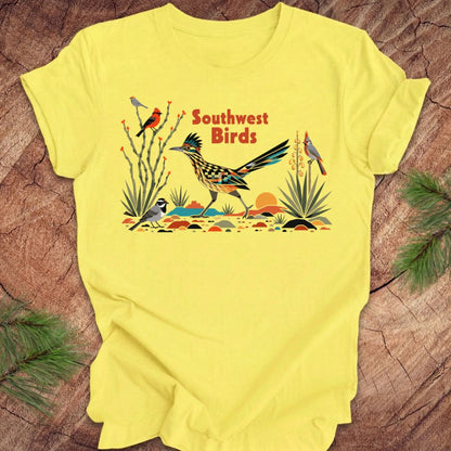 Yellow t-shirt with a colorful graphic of birds and 'Southwest Birds' text on a wooden surface.