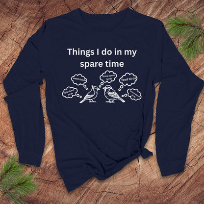 Navy blue long-sleeve tshirt with white text 'things i do in my spare time' with bird graphic and thought bubbles, on a wood surface.