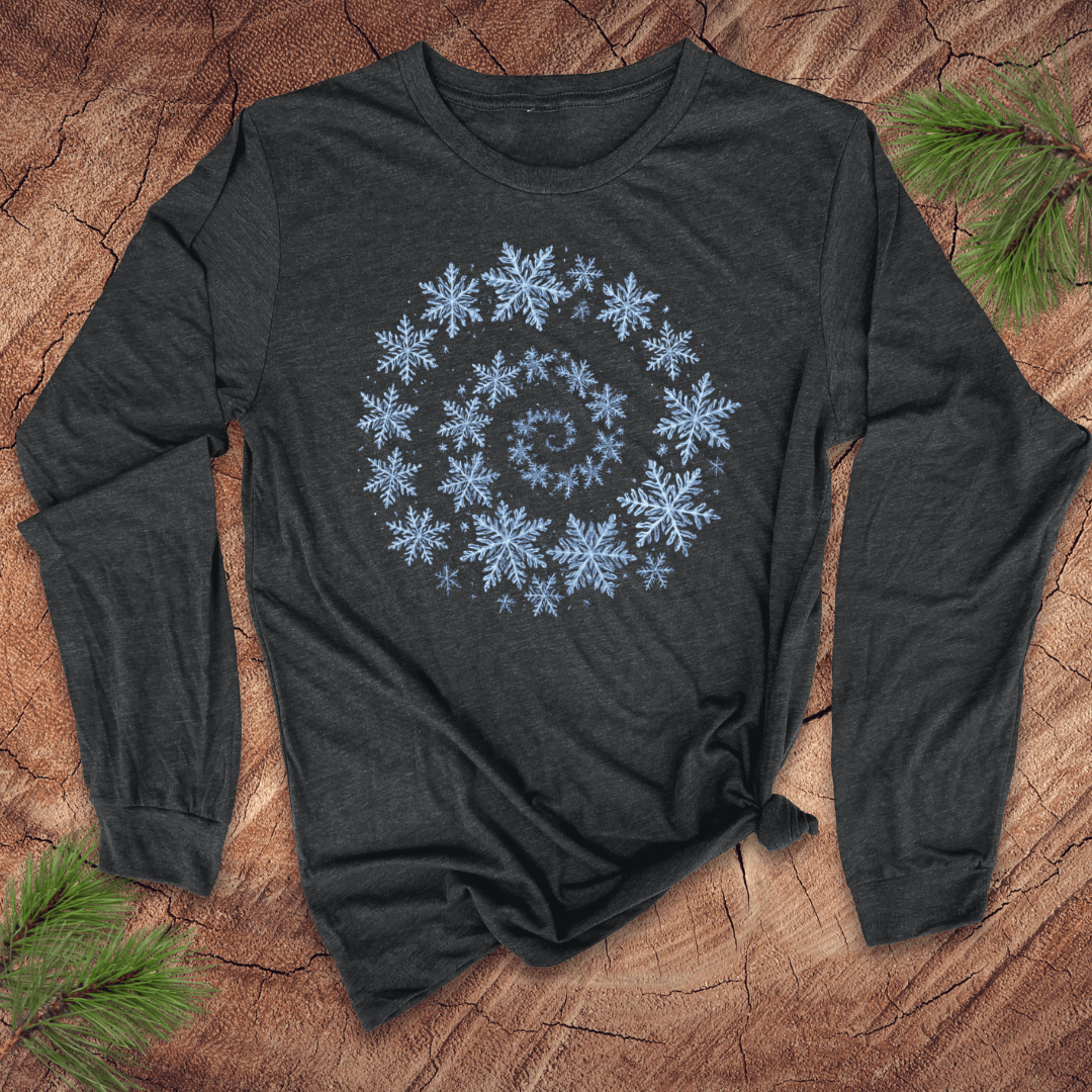 Grey long sleeve shirt with a blue snowflake spiral design on a wooden surface with pine branches.