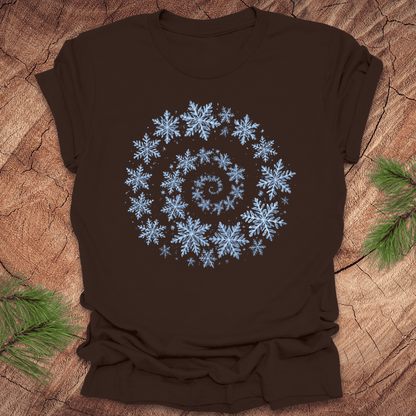Brown t-shirt with a spiral pattern of snowflakes on a wooden surface.