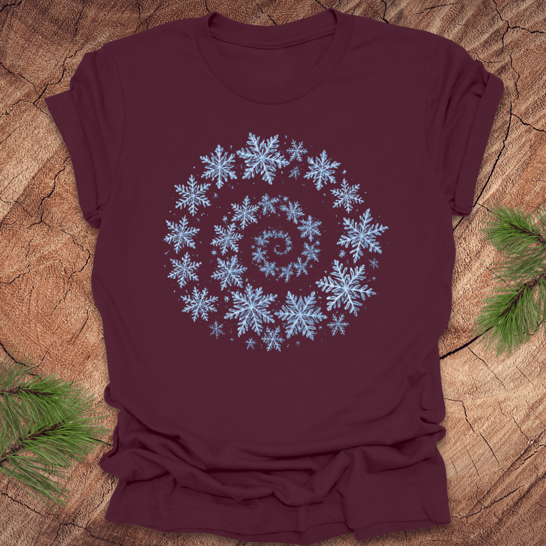 Maroon t-shirt with a spiral pattern of snowflakes on a wooden surface.
