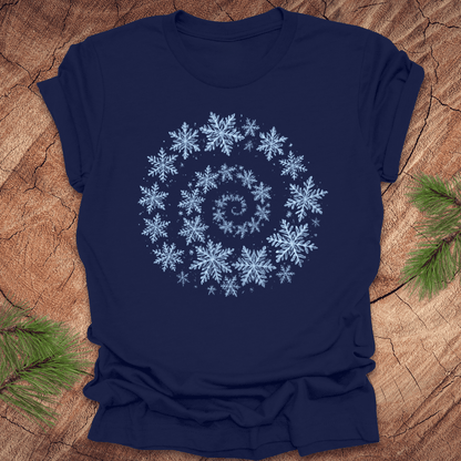 Navy blue t-shirt with a spiral pattern of snowflakes on a wooden surface.