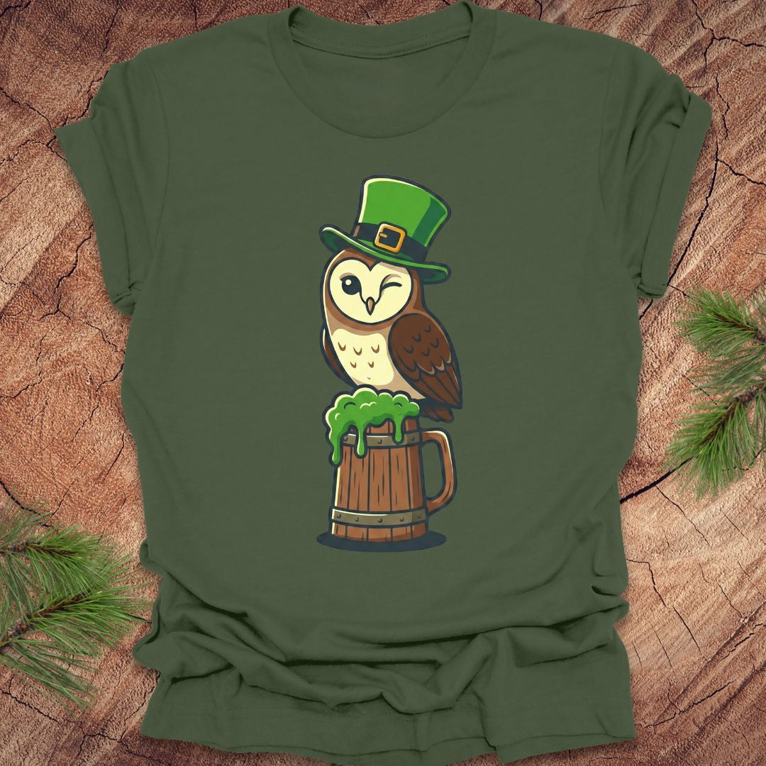 Green t-shirt with an owl design wearing a leprechaun hat on a wooden surface.