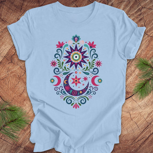 Light blue t-shirt with a colorful mandala design on a wooden surface.