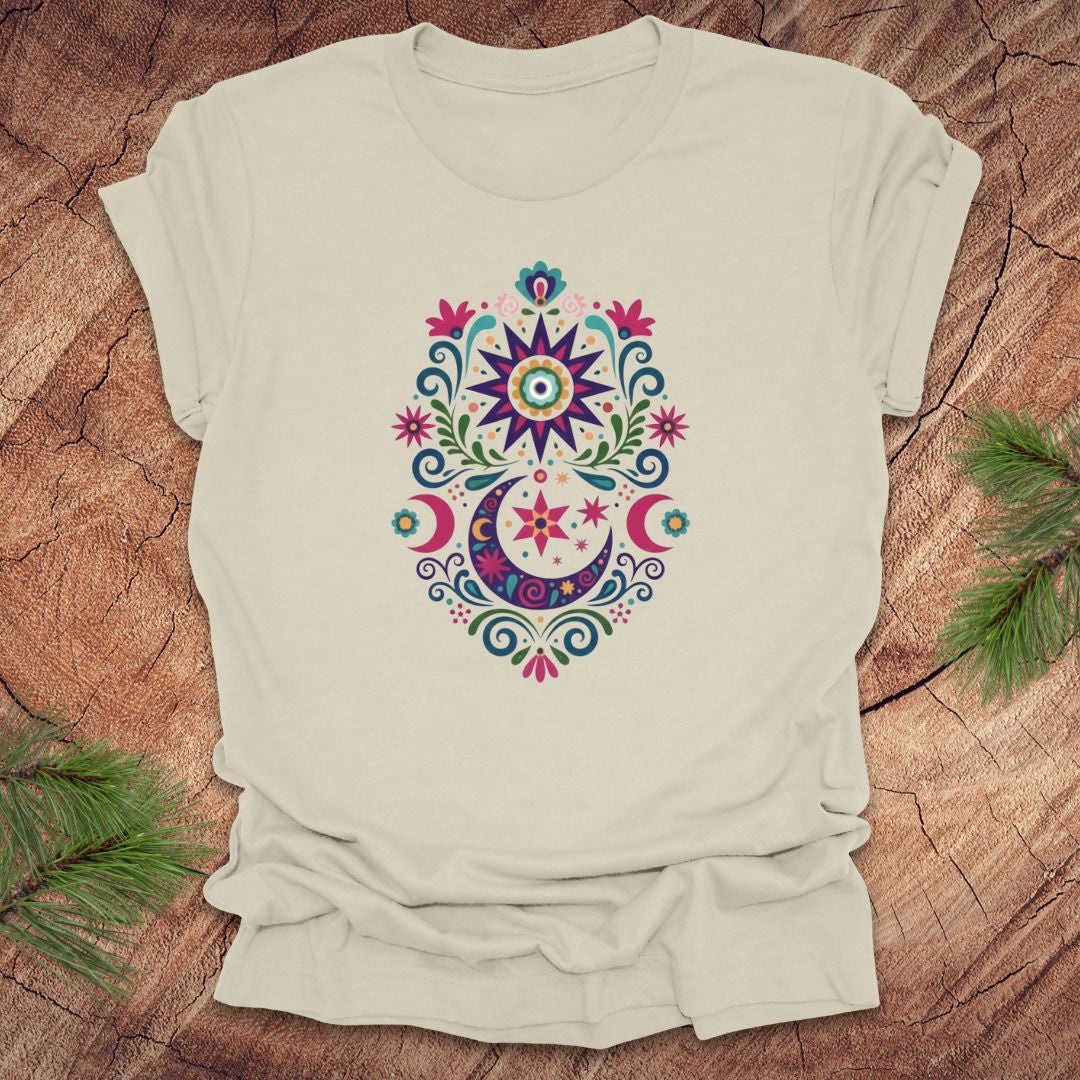 Beige t-shirt with a colorful moon, stars and flower mandala design on a wooden surface
