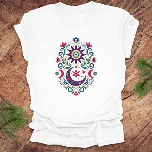 White t-shirt with a colorful moon, stars and flower mandala design on a wooden surface