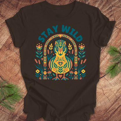 Brown t-shirt with colorful duck graphic and 'Stay Wild' text on a wooden surface.