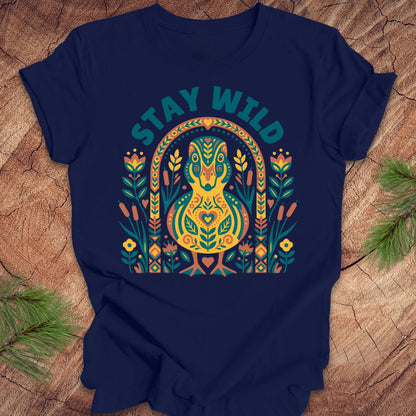 Navy blue t-shirt with colorful duck graphic and 'Stay Wild' text on a wooden surface.