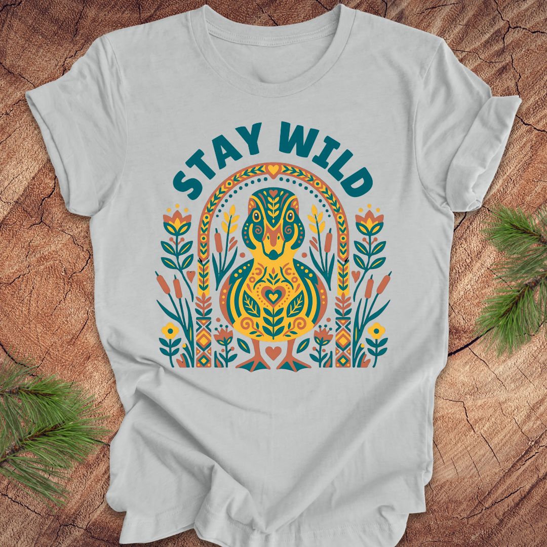 Gray t-shirt with colorful duck graphic and 'Stay Wild' text on a wooden surface.