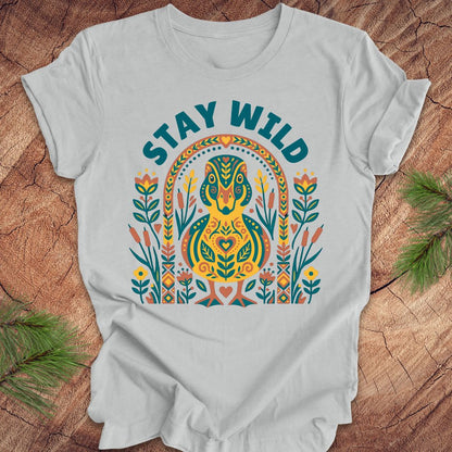 Gray t-shirt with colorful duck graphic and 'Stay Wild' text on a wooden surface.