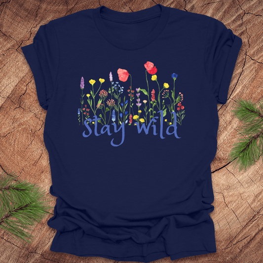 Navy blue tshirt with the text, 'stay wild' with wildflowers on a wooden background.