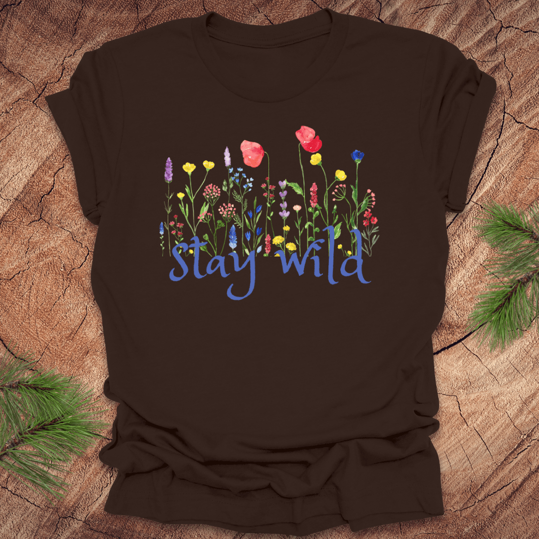 Brown t-shirt with colorful floral design and 'Stay Wild' text on a wooden surface.