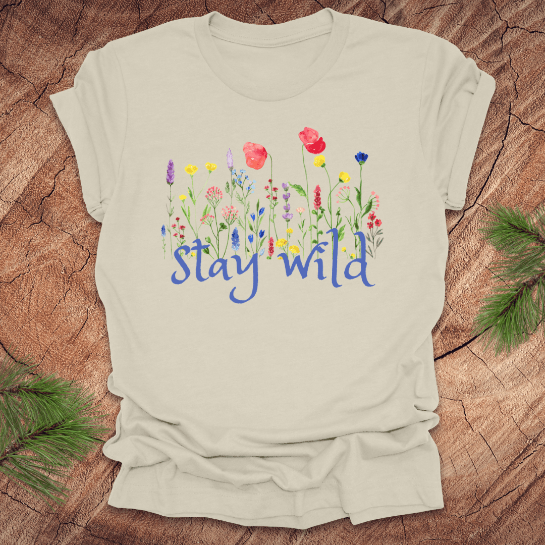 Beige tshirt with the text, 'stay wild' with wildflowers on a wooden background.