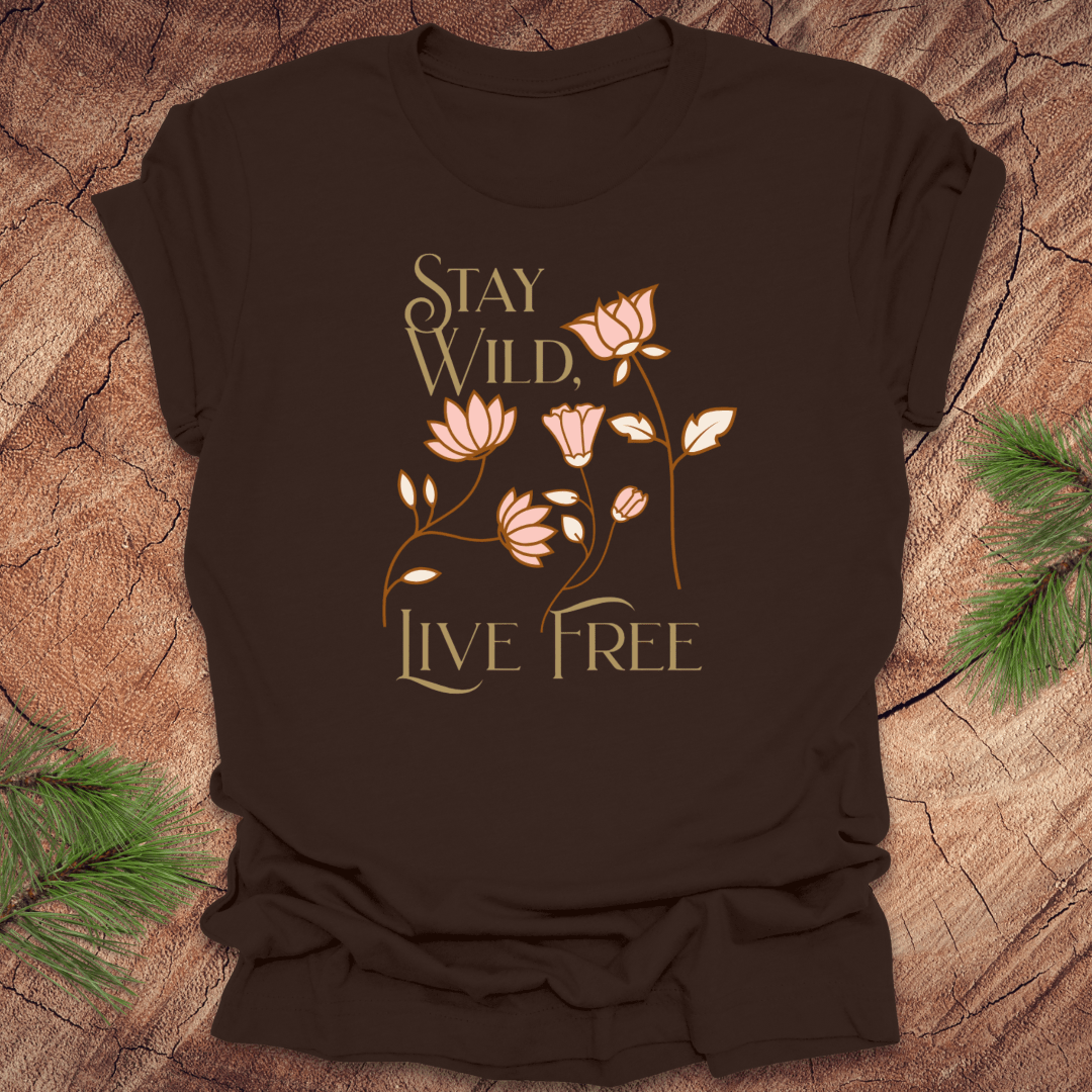 Brown t-shirt with 'Stay Wild, Live Free' text and floral design on a wooden surface.