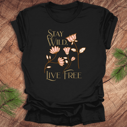 Black t-shirt with 'Stay Wild, Live Free' text and floral design on a wooden surface.