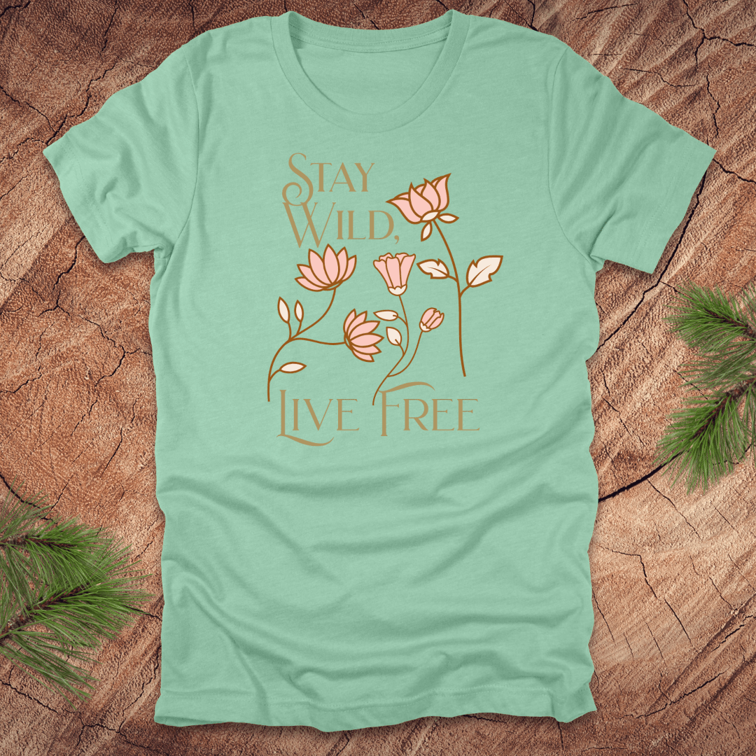 Mint green t-shirt with floral design and text 'stay wild live free' on a wooden surface