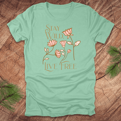 Mint green t-shirt with floral design and text 'stay wild live free' on a wooden surface