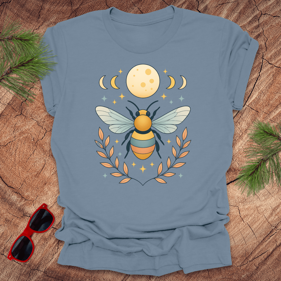 Steel blue tshirt with a bee and moon graphic on a wood background.