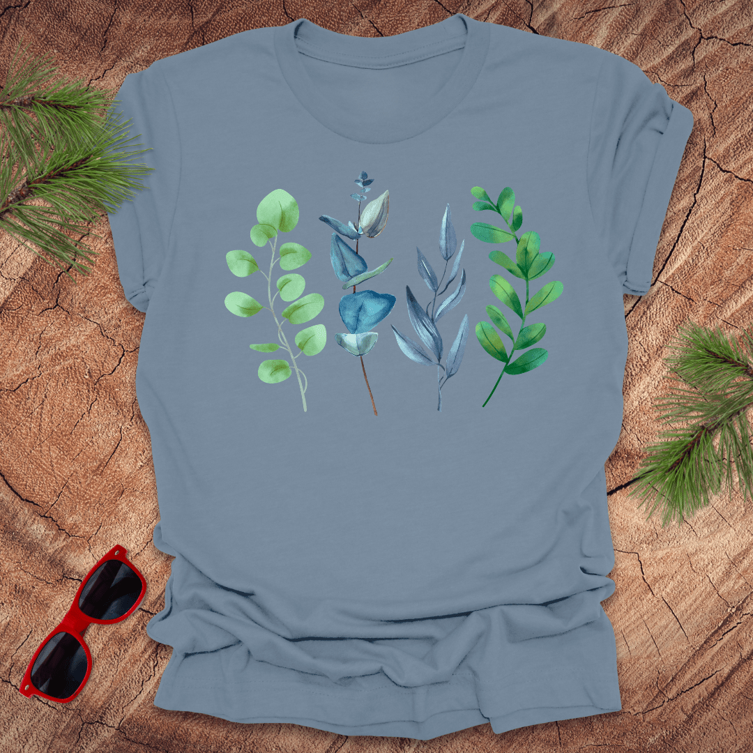 Blue t-shirt with leaf design on a wooden surface with sunglasses and greenery.