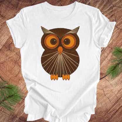 White colored t-shirt with a vintage owl design on a wooden surface