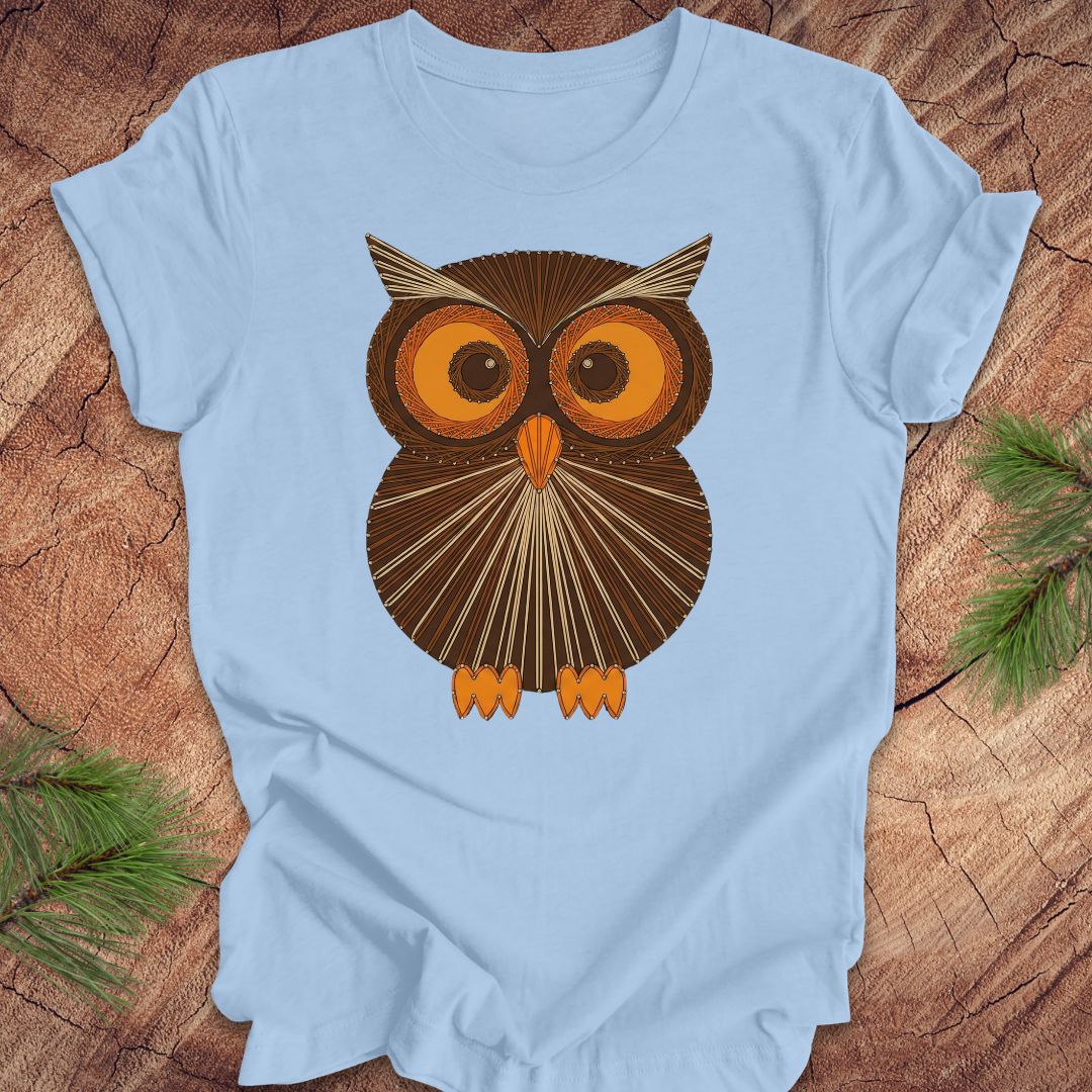 Light blue colored t-shirt with a vintage owl design on a wooden surface