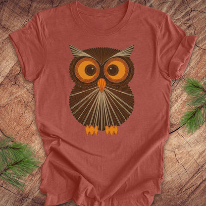 Clay colored t-shirt with a vintage owl design on a wooden surface