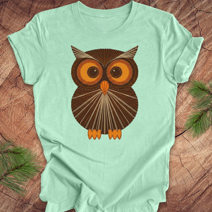 Mint green colored t-shirt with a vintage owl design on a wooden surface